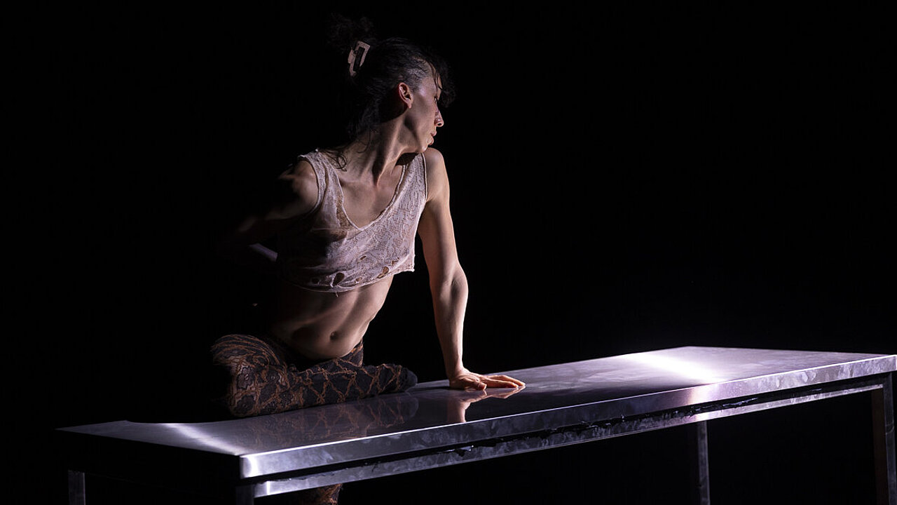 Taous Bertrand sitting on a table, in the dark
