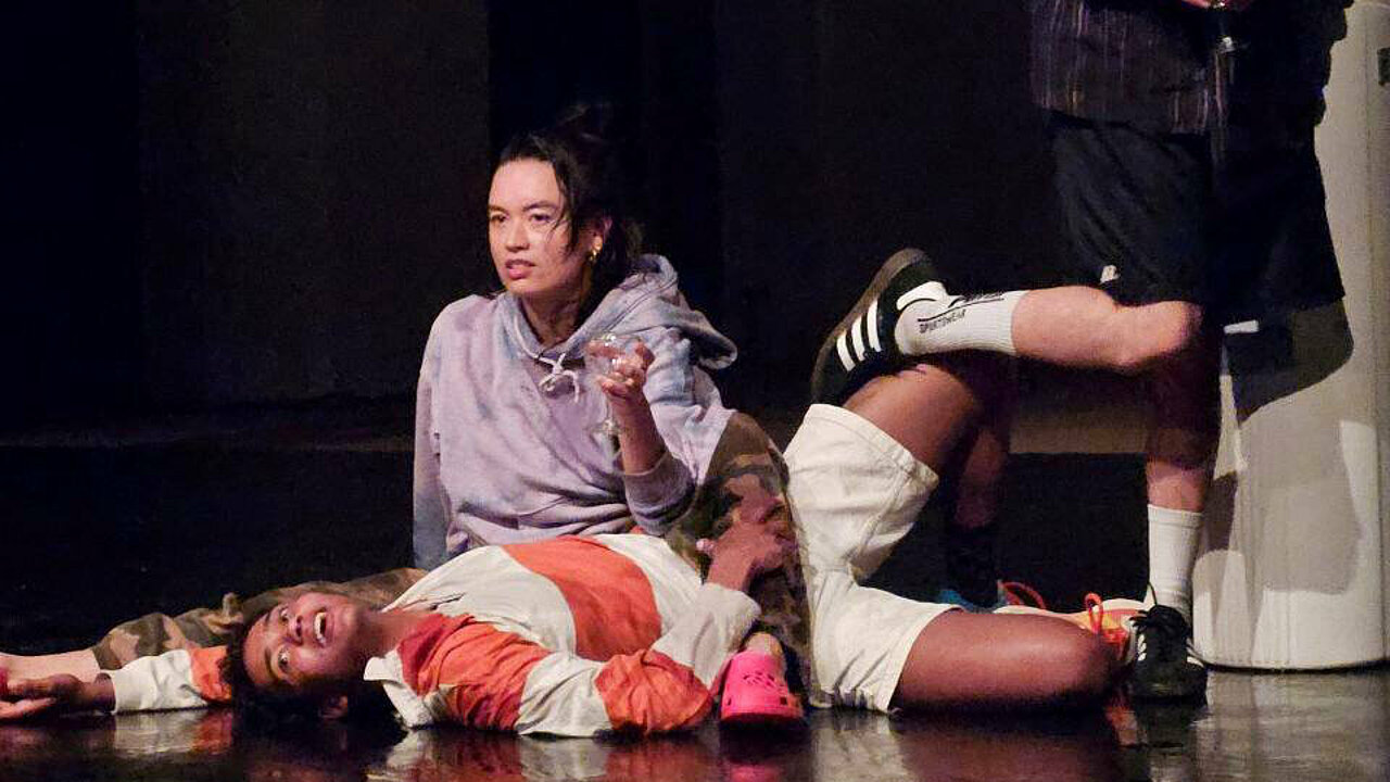 three people on stage, sort of knotted into each other.