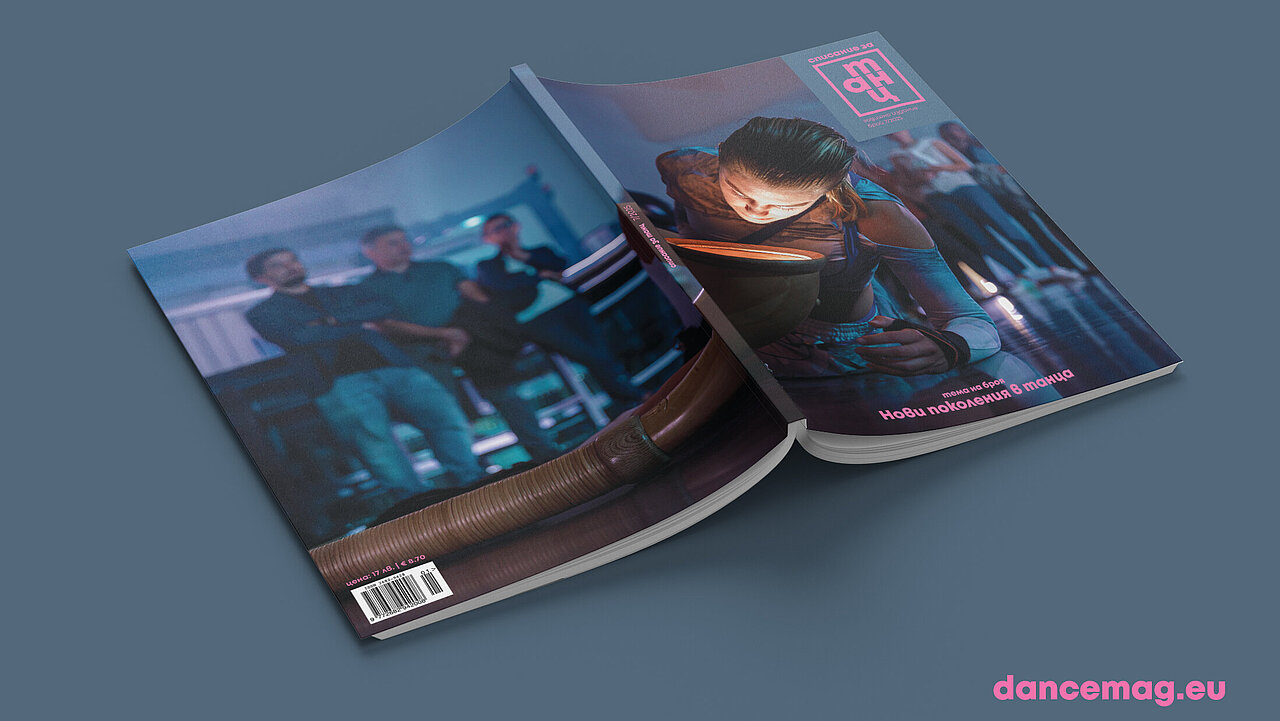Magazin, with the opened pages turned towards the grey surface it is lying on. On the cover a dancer with her face very close, almost as if looking into a  headlight. in the background, blurry, audience standing and watching.