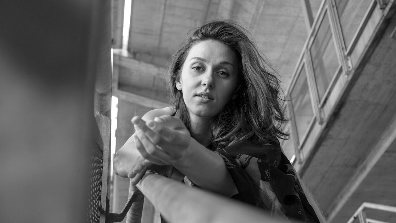Portrait of Anđela Žugić, from below, she is reaching towards the camera, black & white