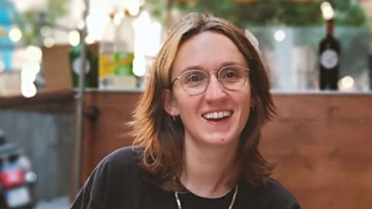 Portrait of Marianne Huber, sitting in a Cafe, with a big smile on her face.