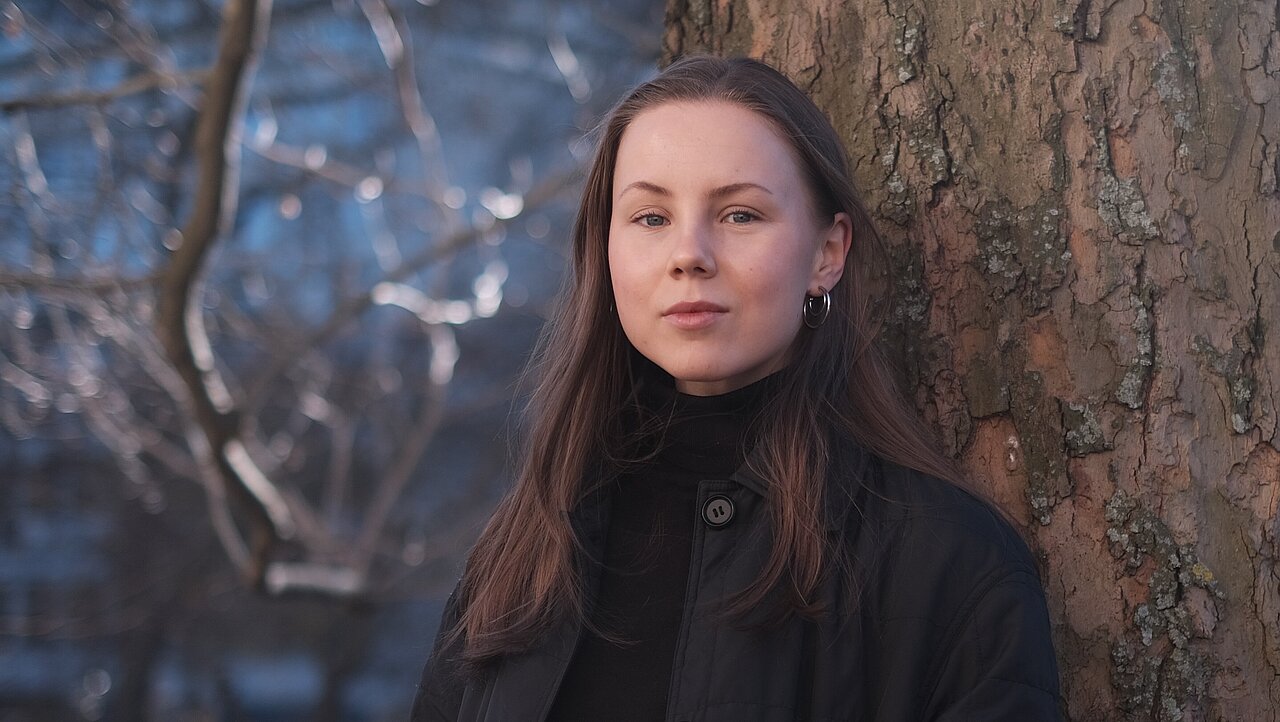 Heta Asikainen leaning against a tree.