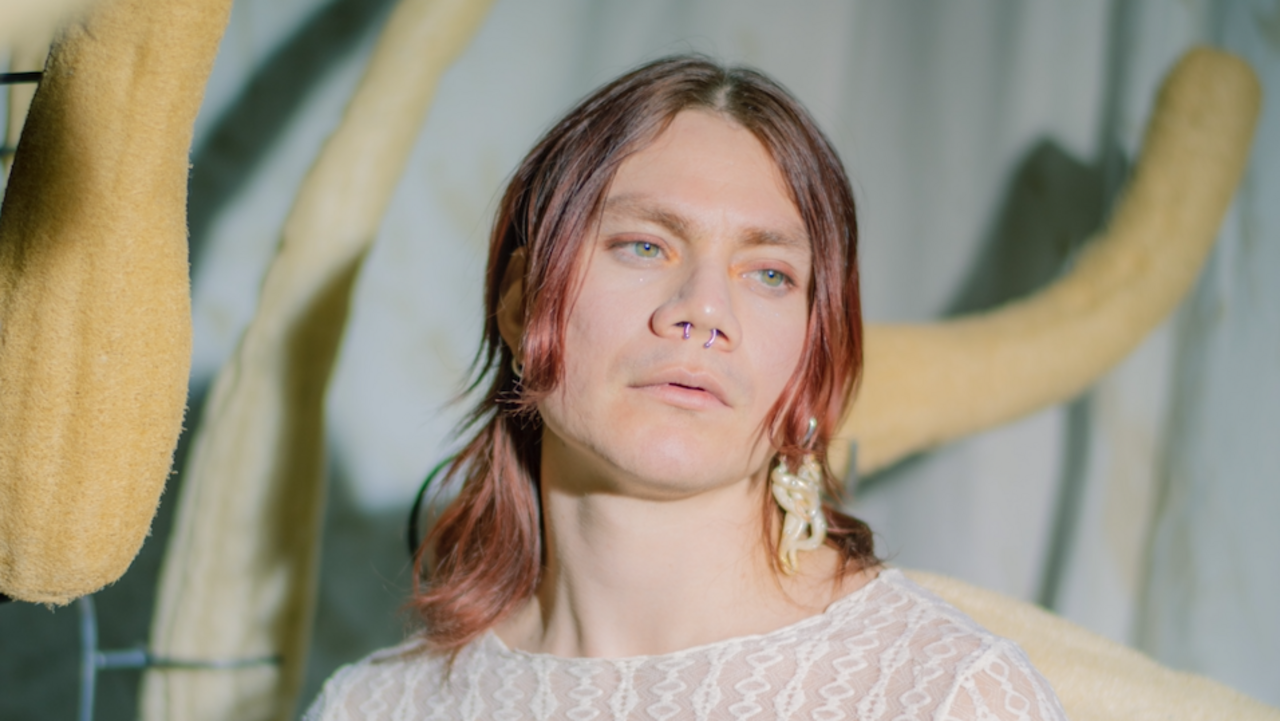 Valentino Skarwan in a see through shirt with Plastic Nipüples attached, surrounded by dried hanging sea cucumbers