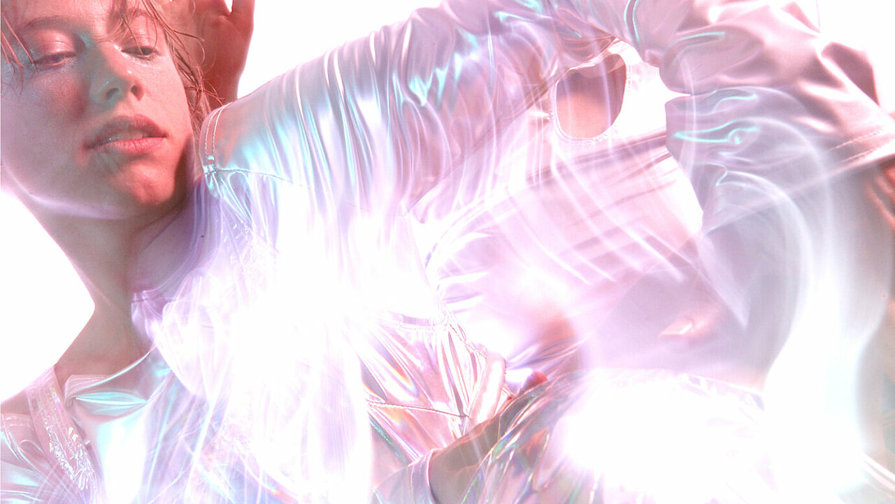 Scene from Softwareness, face with closed eyes, mirroring, shiny fabric