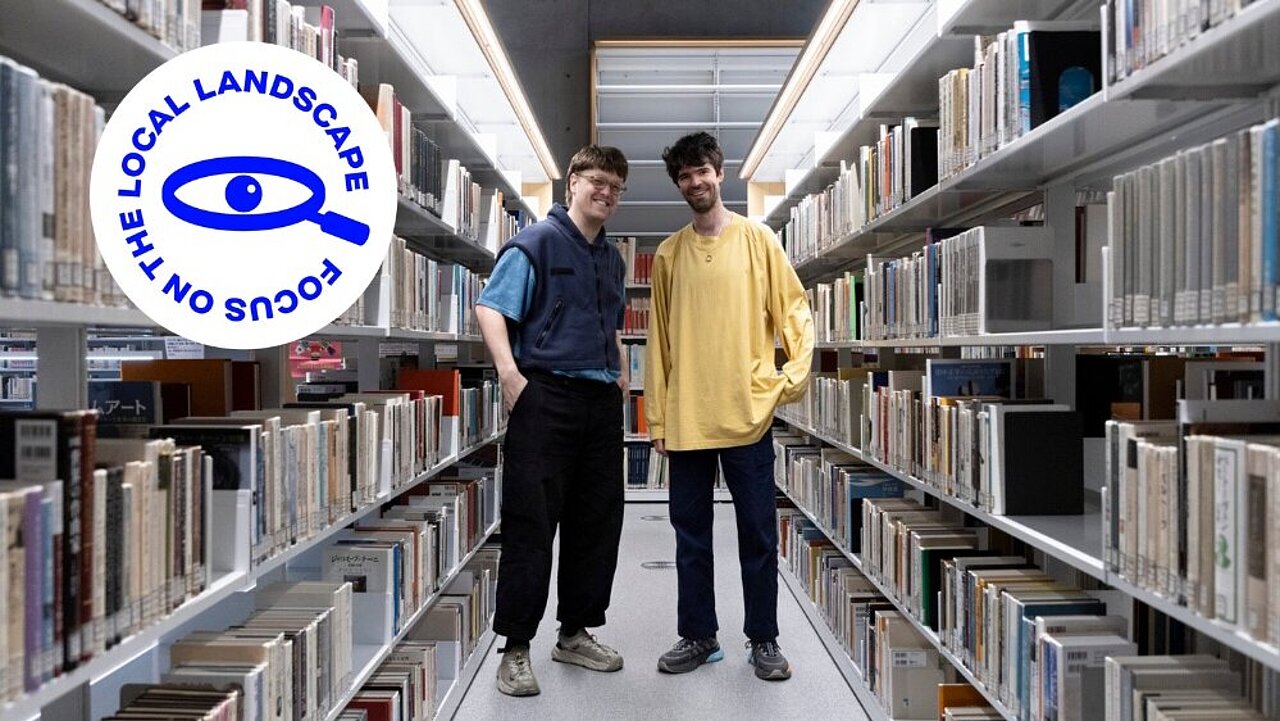 Adam Kinner & Christopher Willes standing in a library.