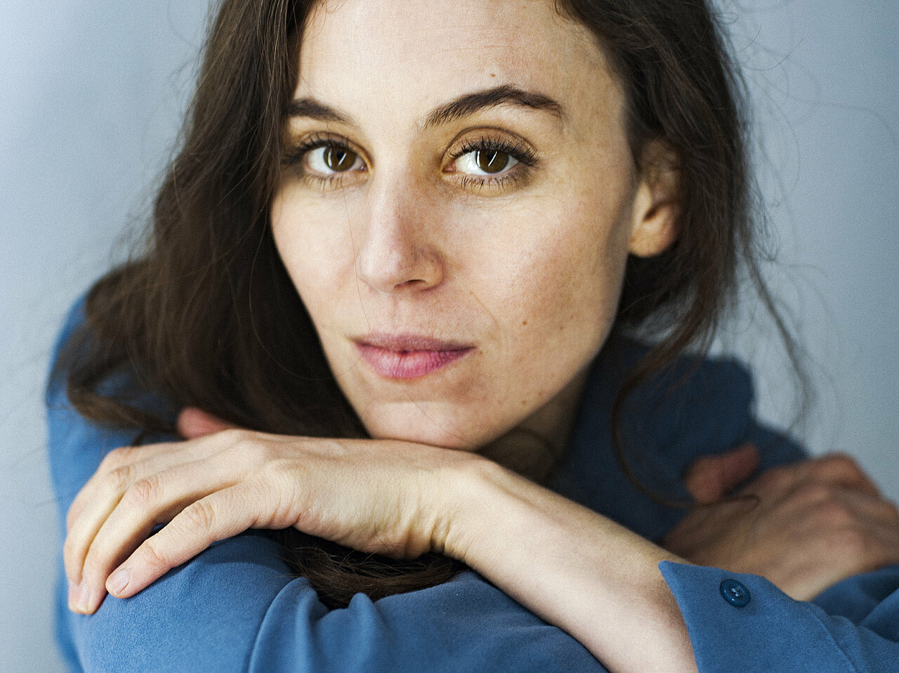 Portrait of Jasmin İhraç, hugging her knees with her arms, leaning her chin on it.