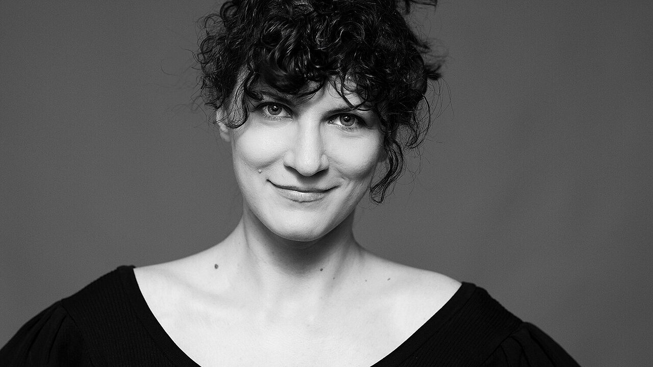 Portrait of Teodora Simova, black and white, smiling face surrounded by black curls.