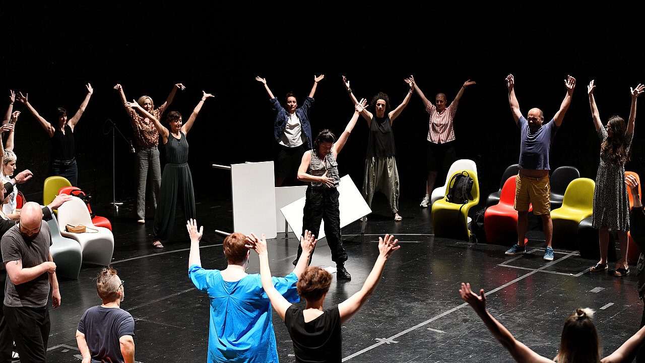 Performers in a circle, with the hands up in the air.