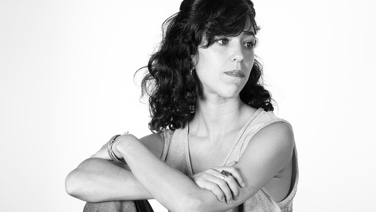 Chen Nadler sitiing on a stool, leaning on her right knee.
