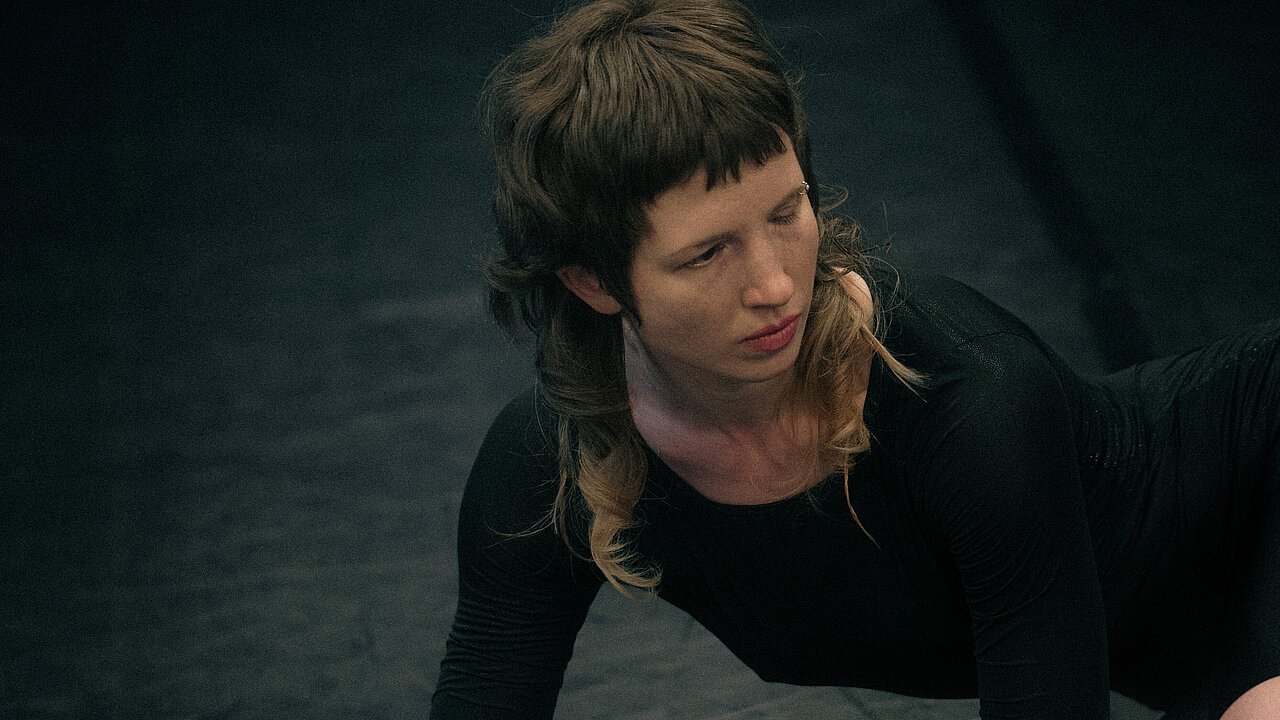 Helén lying sideways on the floor, lifting herself up with her arms