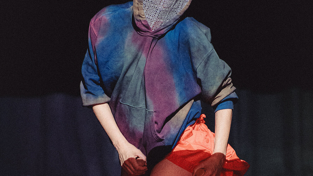 a dancer on their knees, the opening of the hoody coverd in lace, showing one thigh.