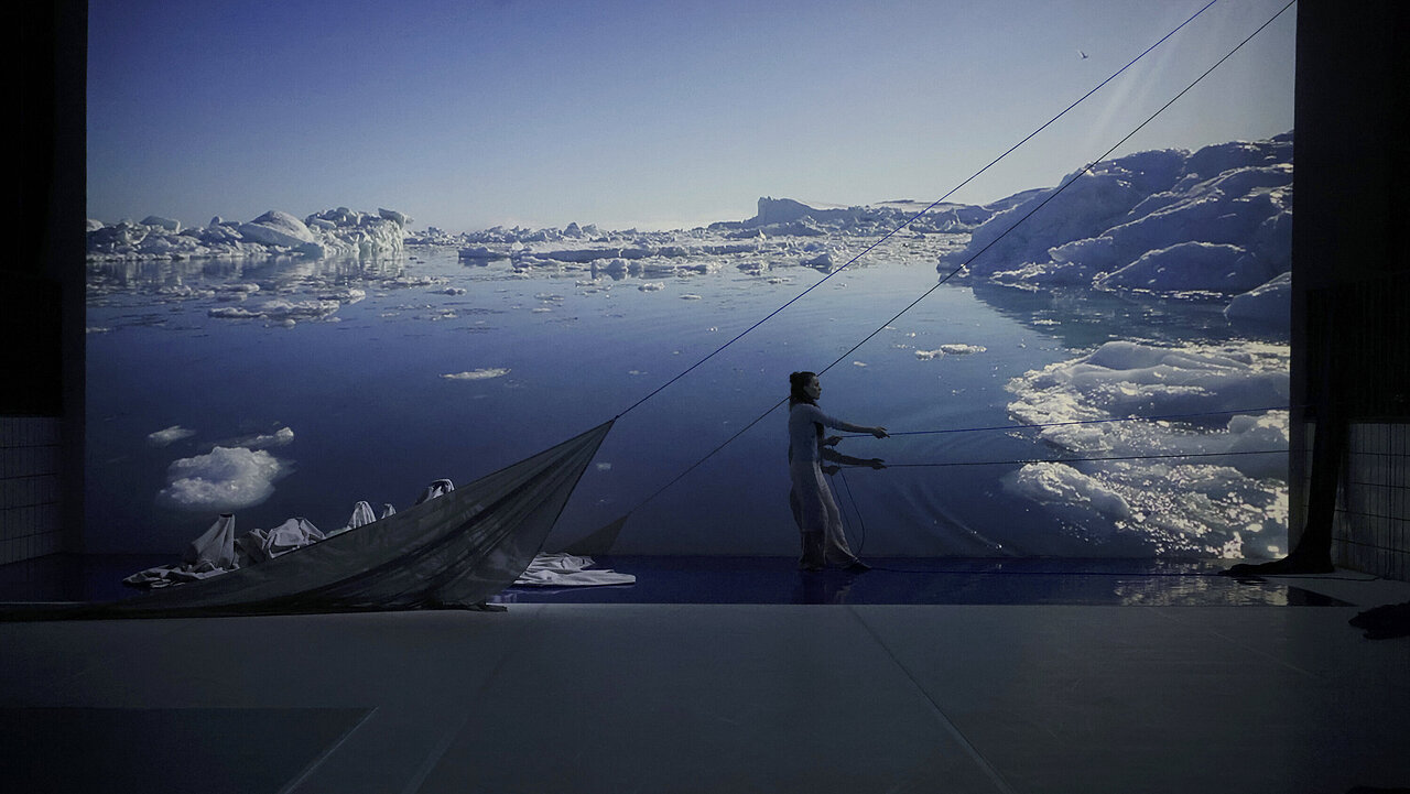 Jasmin in front of a big screen, showing the arctic ice.