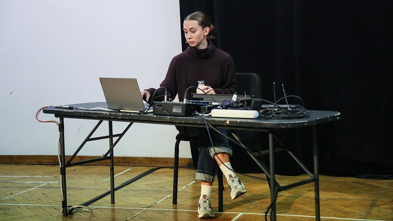 Anna Javoran sitting at a desk filled with technical equipment and a laptop