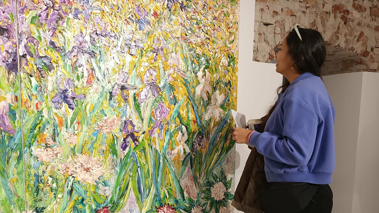 Andrea Vezga looking at an enormous painting of flowers
