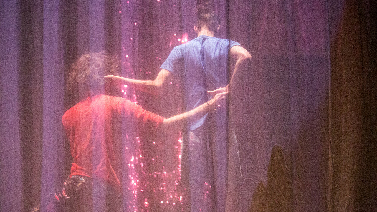 Two dancers behind a see trough curtain